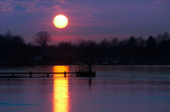 Sunset over frozen lake with dock silhouette