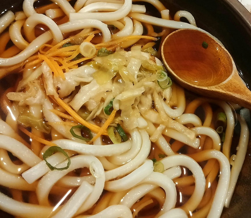 Japanese Udon Noodle Soup With Toppings And Wooden Spoon