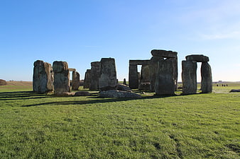 Stonehenge monument on green grass under clear blue sky