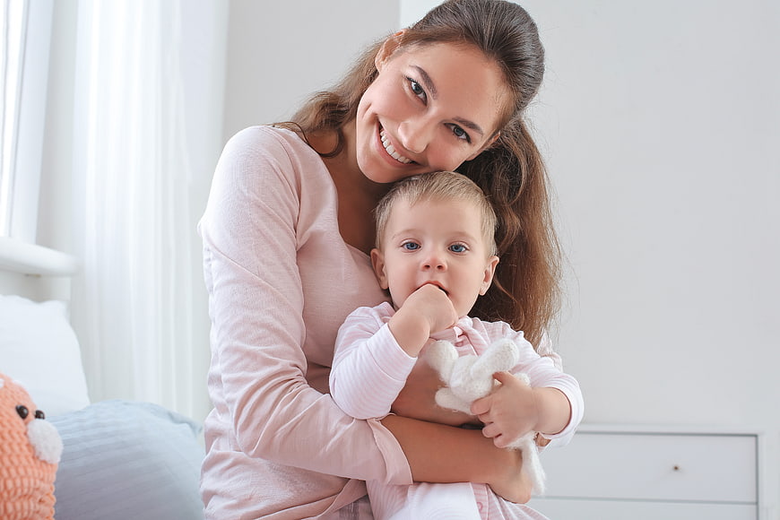 Happy Mother Holding Toddler with Stuffed Toy
