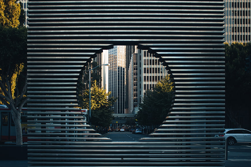 Modern metal slat sculpture framing city street view