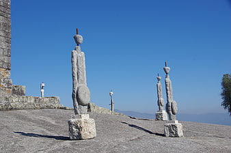 Stone statues on castle ramparts against blue sky