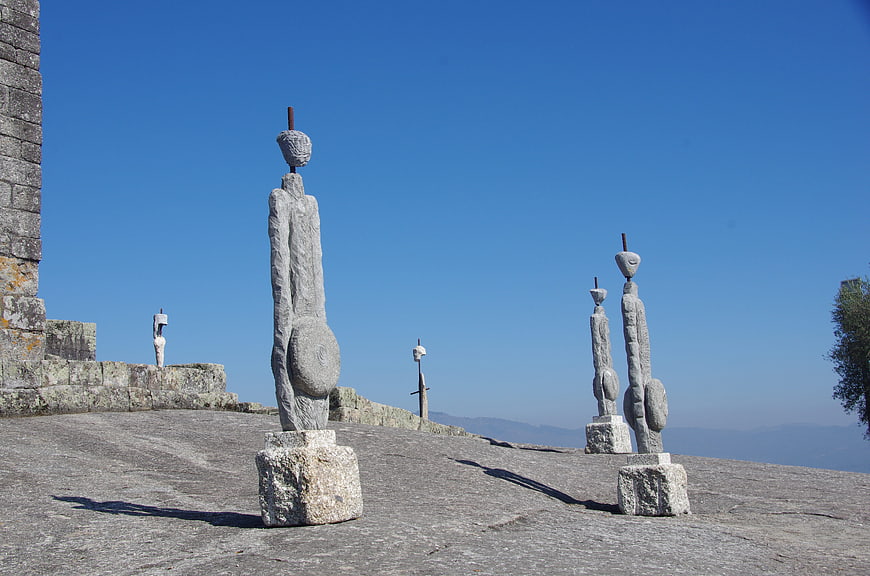 Stone statues on castle ramparts against blue sky