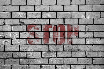 Red Stop Graffiti on Weathered Gray Brick Wall