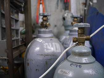 Gray industrial gas cylinders with brass valves in workshop