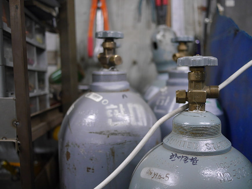 Gray industrial gas cylinders with brass valves in workshop