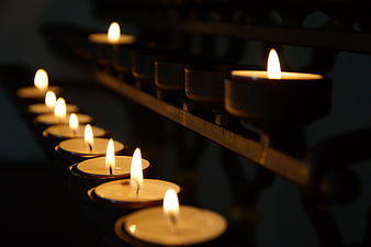 Row of lit tea light candles in a dark church setting