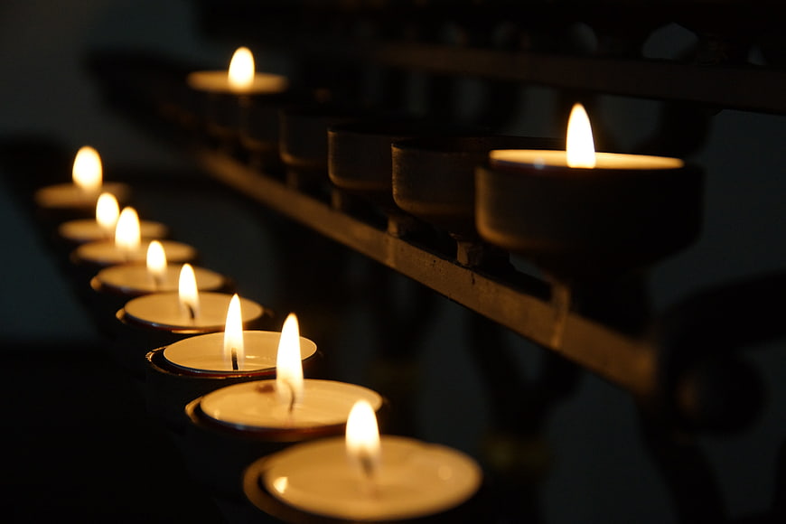 Row of lit tea light candles in a dark church setting