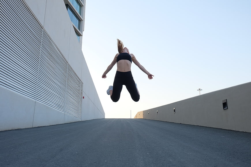 Woman jumping in black activewear on urban rooftop