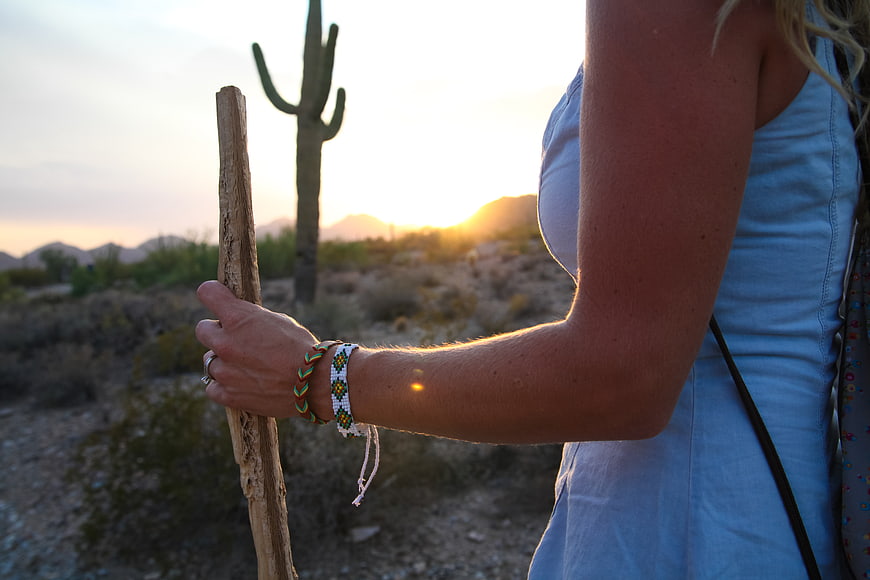 Woman hiking in desert with cactus at sunset