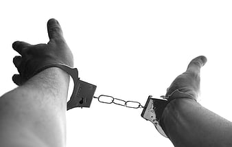 Black and white handcuffed hands reaching upward against white background