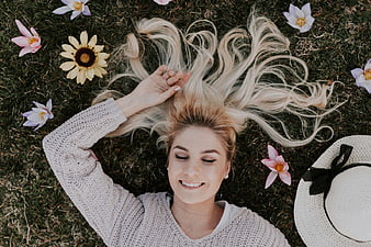 Blonde Woman Lying on Grass Surrounded by Flowers