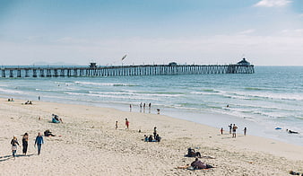 Wide shot of beach with pier and people relaxing