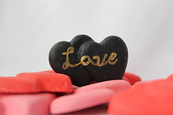 Black heart with gold love text on red and pink hearts