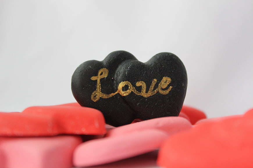 Black heart with gold love text on red and pink hearts