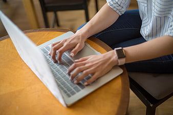 Woman Typing on Laptop at Wooden Table