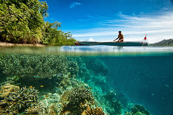 Split-level view of coral reef and outrigger boat in Indonesia