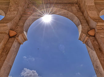 Sunburst Through Moroccan Archway Against Blue Sky