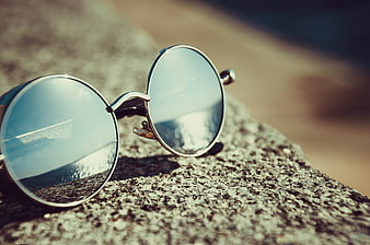 Round Sunglasses Reflecting Beach on Rock