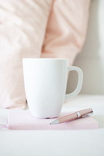 White Mug and Pen on Pink Notebook in Soft Light