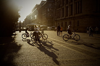 Cyclists and Pedestrians on Cobblestone Street at Golden Hour