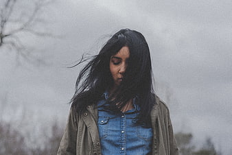 Melancholic woman with windblown hair in denim jacket