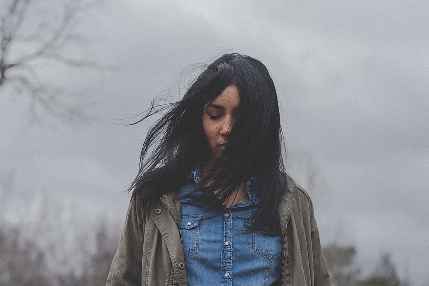 Melancholic woman with windblown hair in denim jacket