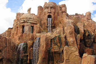 Giant stone face sculpture with waterfall at theme park