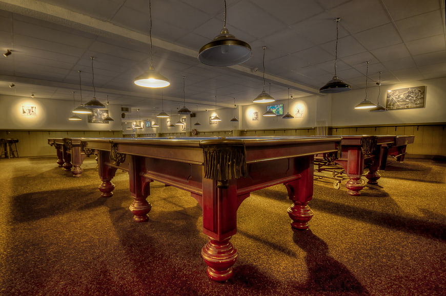 Empty vintage pool hall with red billiard tables and warm lighting