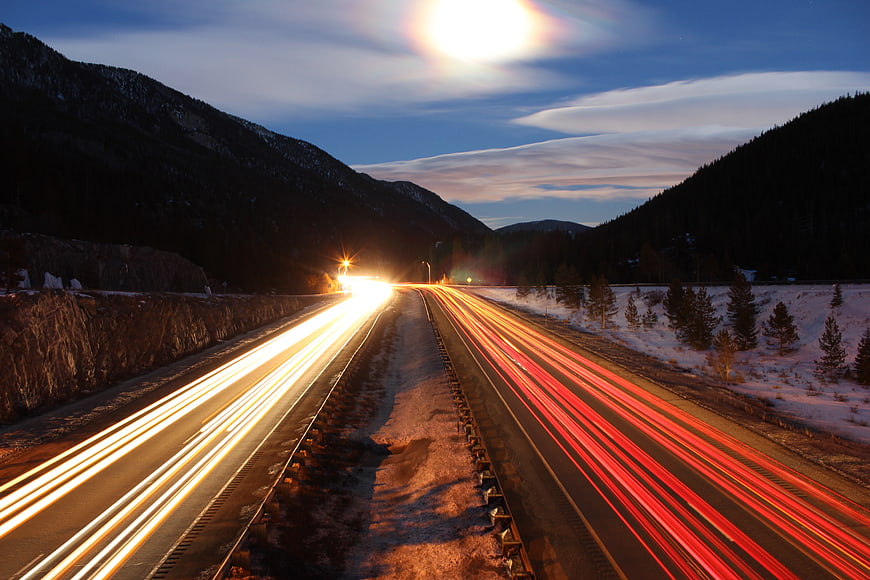 Long Exposure Highway Light Trails in Snowy Mountains at Night