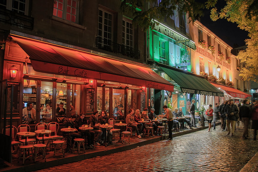 Nighttime Parisian street scene with outdoor cafe seating