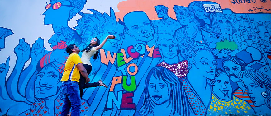 Couple posing in front of colorful Welcome to Pune mural