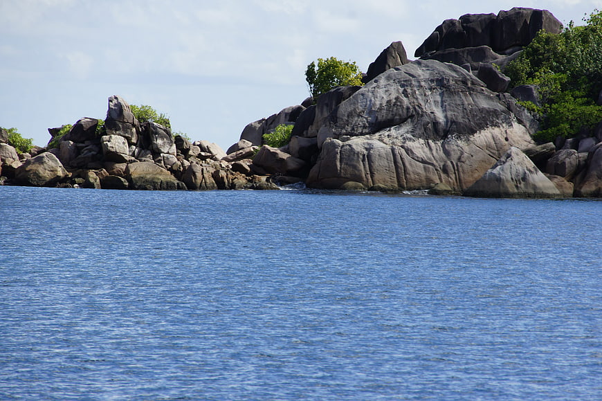 Rugged granite rocks and green vegetation along a blue ocean coastline
