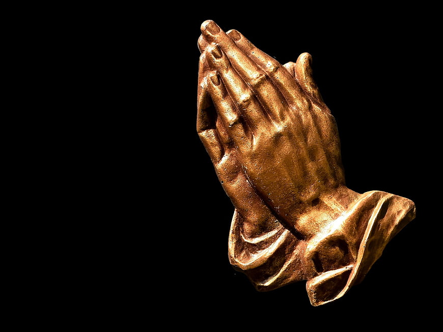 Golden Praying Hands Sculpture on Black Background