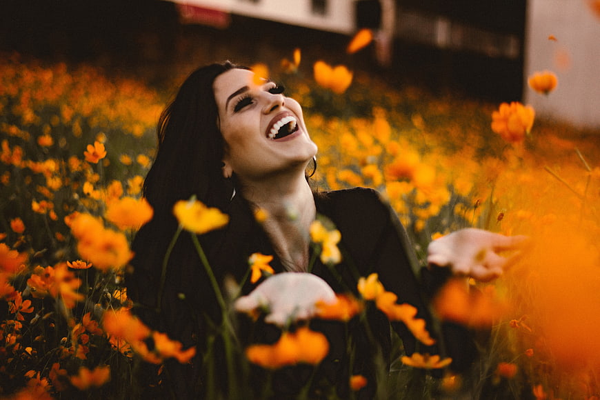 Happy Woman Laughing in Orange Flower Field