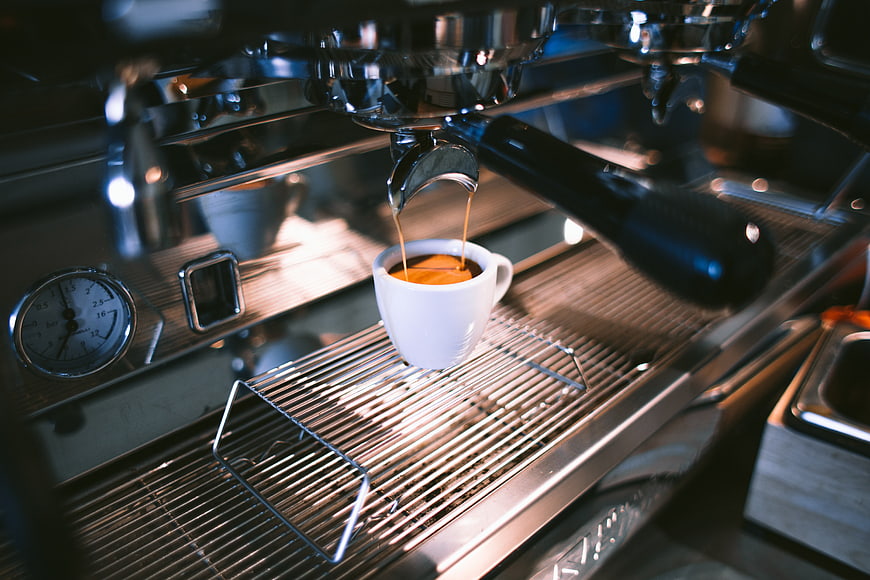 Espresso pouring from machine into white cup
