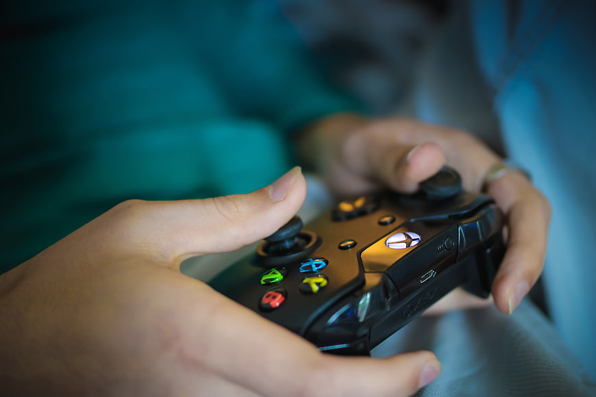 Close-up of hands holding a black Xbox controller