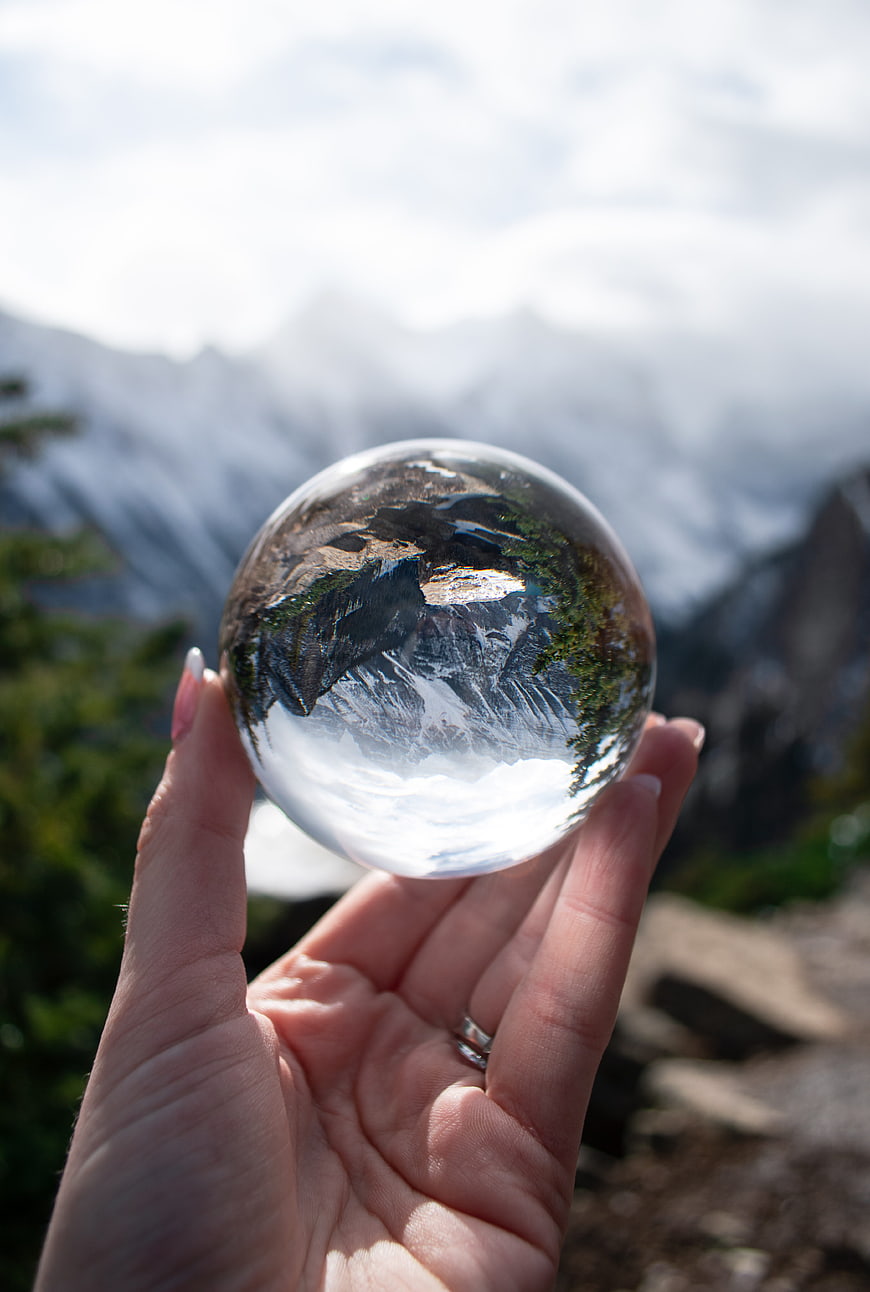 Hand holding crystal ball reflecting mountain landscape