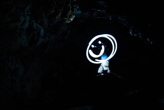Light painting smiley face in dark cave at night