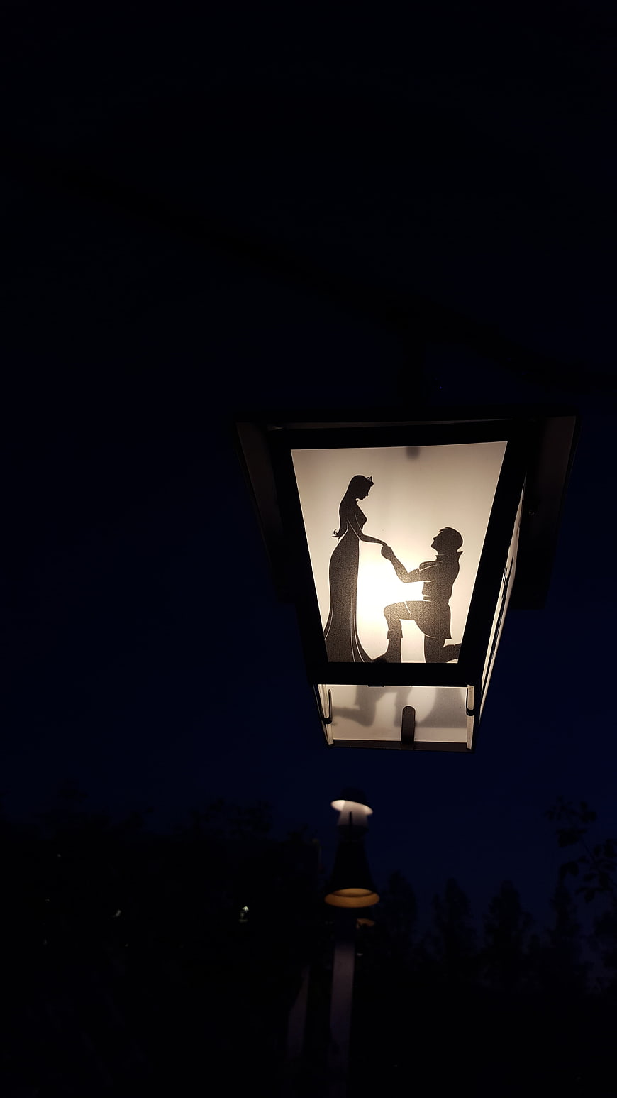 Illuminated street lamp featuring a romantic silhouette of a couple at night