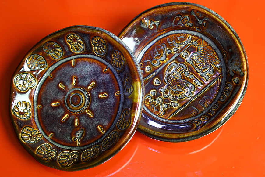 Handmade Ceramic Plates with Embossed Designs on Orange Background