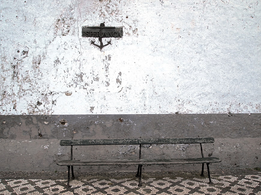 Weathered Bench Against Textured Wall with Esperanca Sign