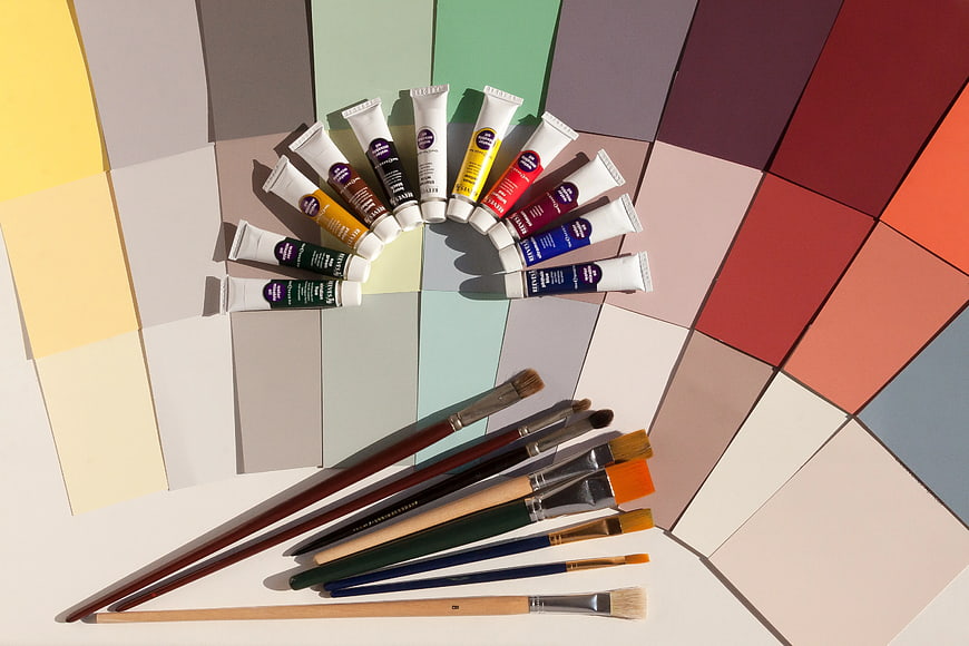 Flat lay of paint tubes and brushes on color swatches