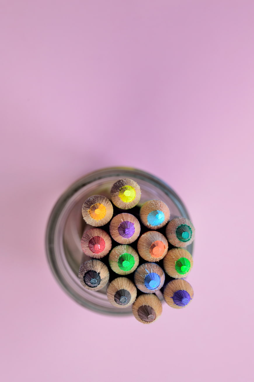 Top View of Colorful Pencils in Glass Jar on Pink Background