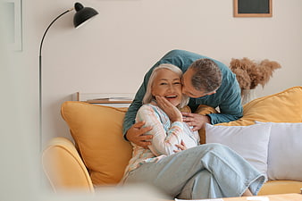 Happy Senior Couple Laughing on Yellow Sofa