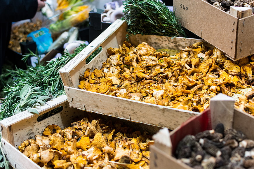 Fresh chanterelle mushrooms and herbs in wooden crates at market