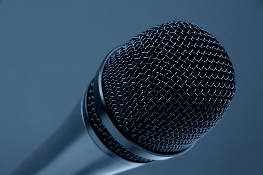 Close-up of black microphone head on blue background