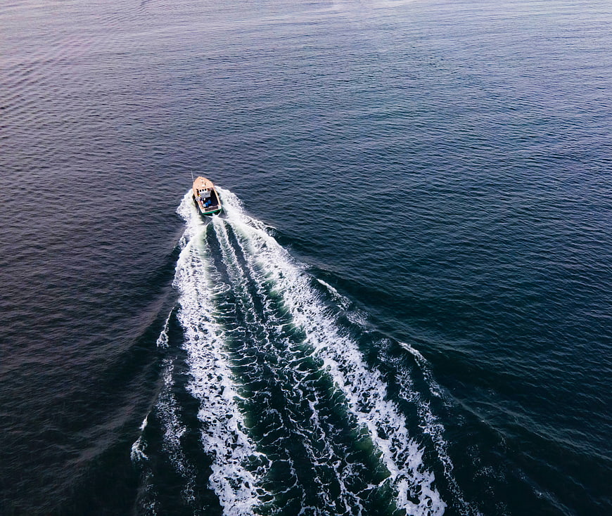 Aerial View of Small Boat Leaving White Wake on Blue Ocean