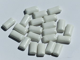 White rectangular chewing gum pieces scattered on a plain white surface