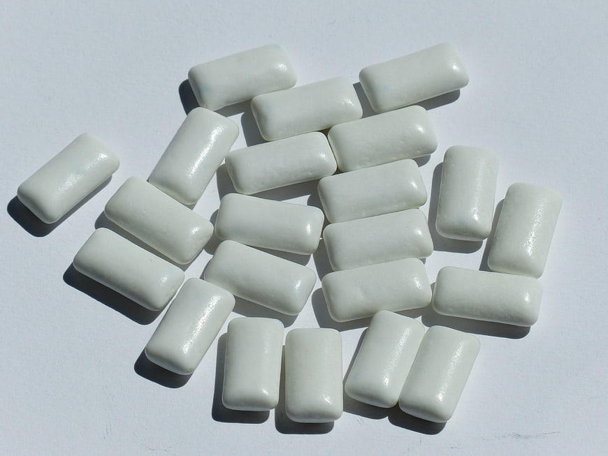 White rectangular chewing gum pieces scattered on a plain white surface